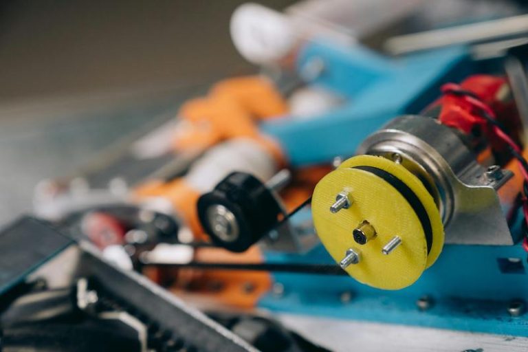 A belt drive in focus with various electronic parts out of focus.
